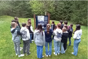 Jugendliche bekommen anhand einer Tafel im Freien etwas erklärt